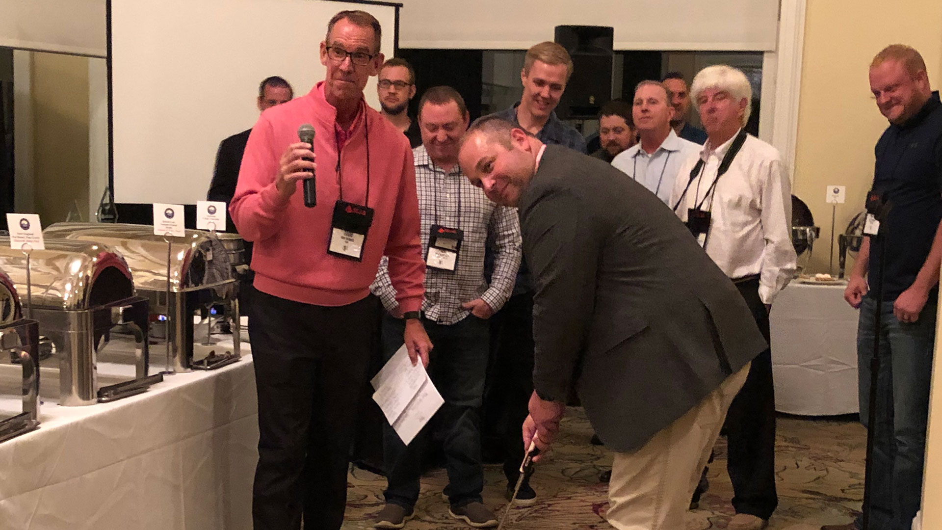 Ron Adams (center) lines up the winning putt at the MCAA Closing Dinner.