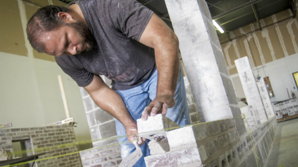 William Kaufmann, a student in the Texas Masonry Council/University of Texas at Arlington - Division for Enterprise Development’s accelerated masonry training certification program works on a panel.