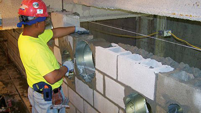 In the photo above, a bricklayer installs mechanical duct sleeves at precise locations per the BIM model, as he constructs the masonry.